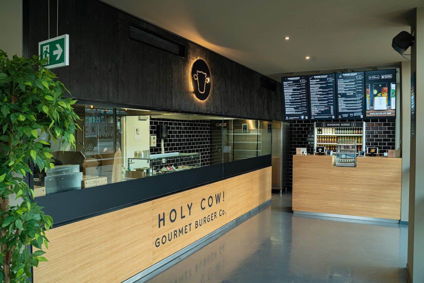Le comptoir du restaurant Holy Cow! à Genève, avec son enseigne et ses écrans de commande