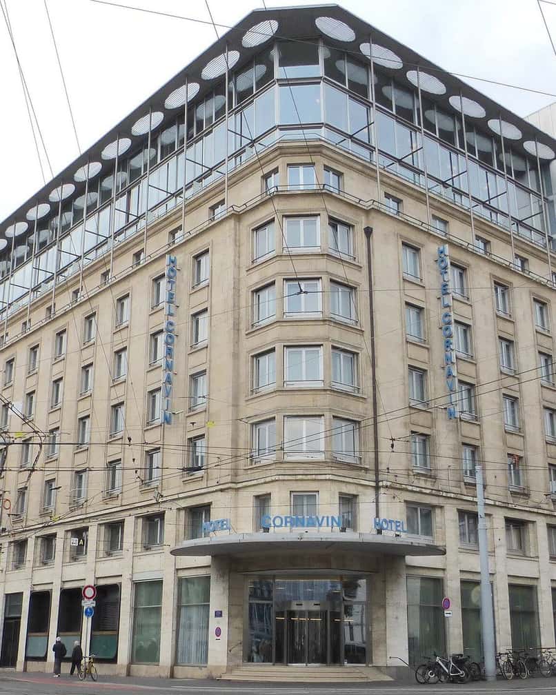 Façade d'un hôtel près de la gare Cornavin à Genève, rue animée avec des voyageurs et leurs valises