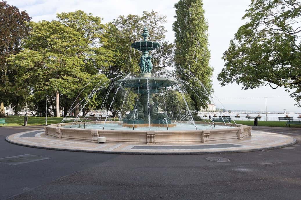 La grande fontaine du Jardin anglais de Genève, entourée d'arbres, au bord du lac
