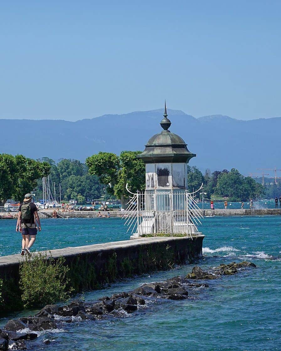 La jetée des Eaux-Vives à Genève avec des promeneurs au pied du Jet d'eau et les embruns portés par le vent