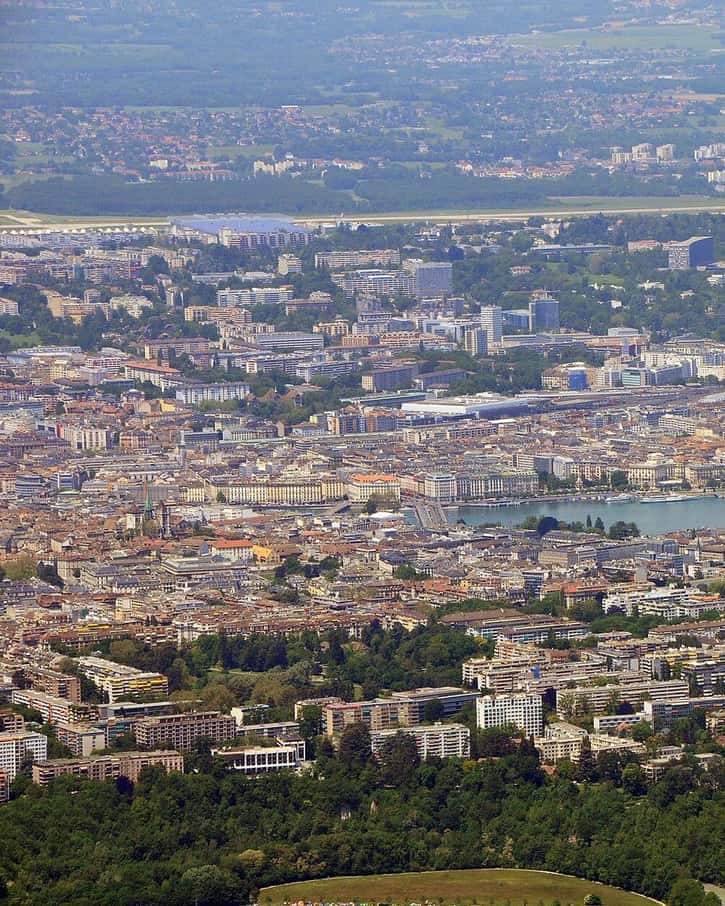 La rade de Genève vue depuis le pont du Mont-Blanc, avec le Jet d'eau, les quais et les montagnes au loin