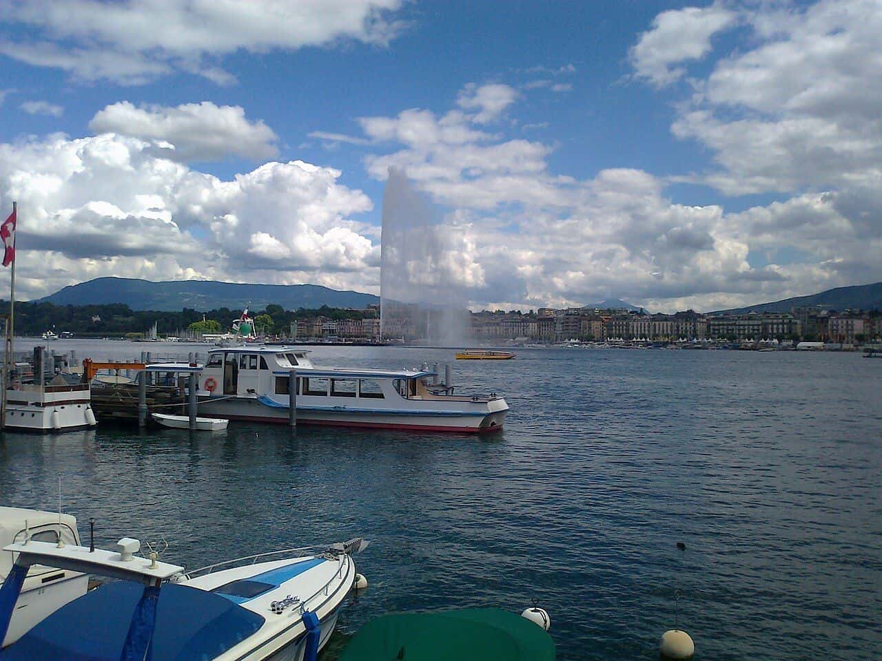 La rade de Genève et le Jet d'eau, avec des bateaux amarrés au premier plan et le Salève au loin