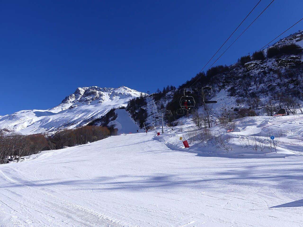 Un télésiège au-dessus d'une piste enneigée dans les Alpes françaises, par une journée ensoleillée