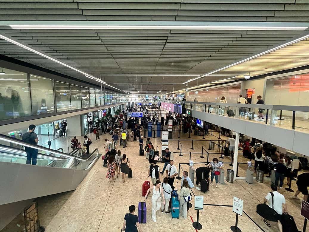 Le hall de l'aéroport de Genève, avec les voyageurs et leurs valises sous la grande verrière